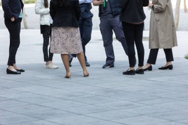 Bir grup insan dışarıda, fayanslarla döşenmiş zeminde toplanıyor.