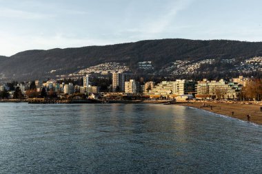 Vancouver, Kanada 'da arka planda binaları olan plajdaki insanlar.
