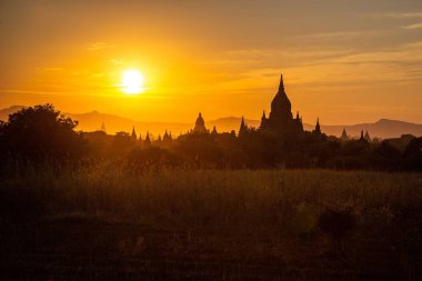 Bagan 'ın bazı tapınaklarının kuleleri Myanmar' da batan güneş tarafından siluetlenmiştir..