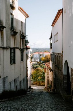 İki eski bina arasındaki dar bir tuğla sokağın dikey görüntüsü.