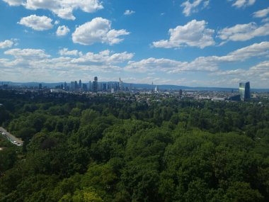 Güneşli bir günde yeşil ağaçların arkasındaki havadan bir şehir.