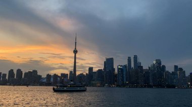 Gölde yüzen Toronto şehrinin arka planında günbatımında ufuk çizgisi olan bir gemi