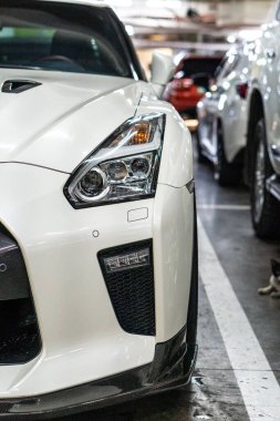 Park yerindeki beyaz Nissan GT-R spor arabasının dikey görüntüsü.