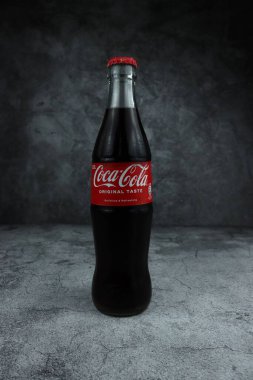 Modern koyu taşlı arka plana karşı Coca Cola şişesinin dikey çekimi.