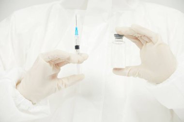 Ellerinde şırınga ve cam tüp tutan bir doktor.