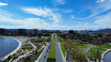 Parkın yakınındaki otoyollara ve mavi bulutlu gökyüzünün altındaki göle kuş bakışı bir bakış.