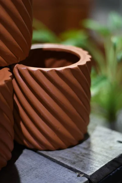 stock image A vertical selective focus of clay terracotta pots on a wooden table with plants in the background