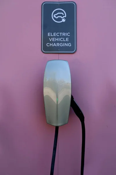 ピンクの壁の上に電気自動車の充電器とそのサインの垂直閉鎖ショット — ストック写真