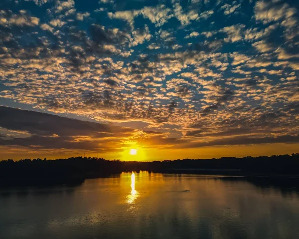 美しい曇天の森と湖の地平線に沈む黄金の太陽の風景 — ストック写真