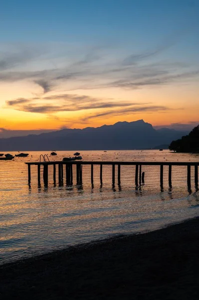 Günbatımında Garda Gölü Kıyısındaki Bir Rıhtımın Dikey Görüntüsü Arka Planda — Stok fotoğraf