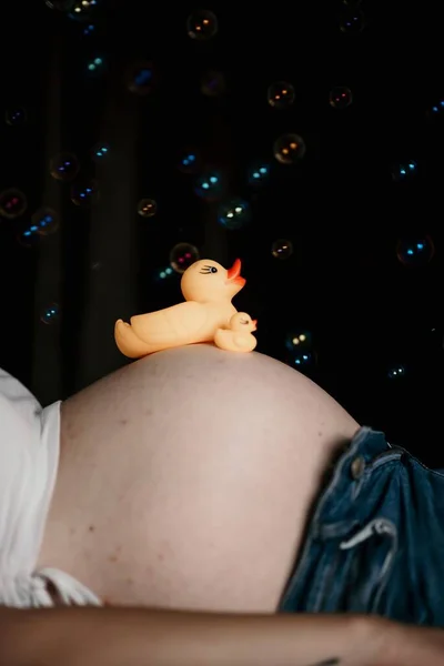 妊娠中の女性の腹におもちゃのアヒルの垂直ショット — ストック写真