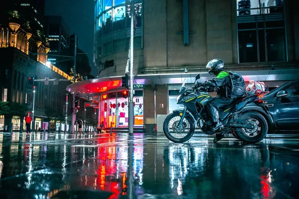 Motocyklista Zatrzymuje Się Światłach Deszczową Noc Świecącymi Latarniami Ulicznymi — Zdjęcie stockowe