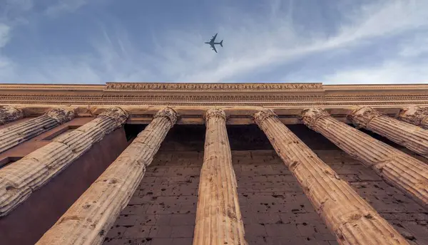 Antik Sütunların Alçak Açılı Bir Görüntüsü Gökyüzünde Uçan Bir Uçak — Stok fotoğraf