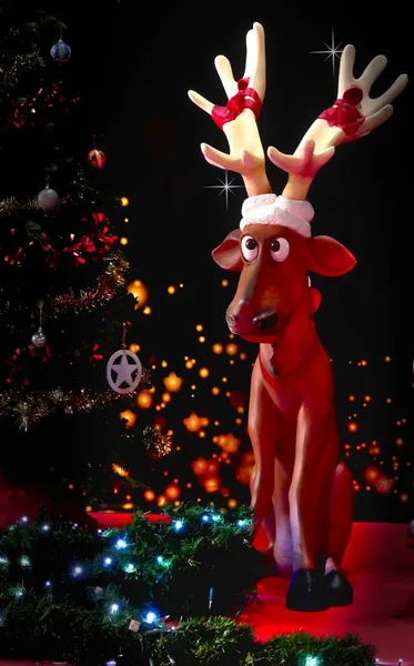 Vertical Shot Reindeer Figure Sitting Next Christmas Tree Illuminated Lights — Stock Photo, Image