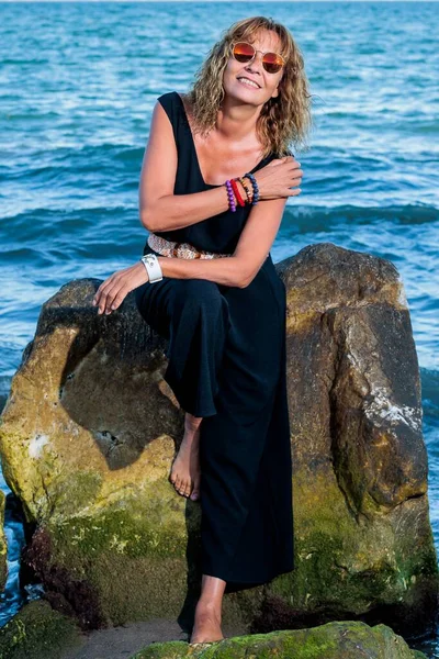 stock image A vertical of a smiling Hispanic woman in black dress posing on the beach