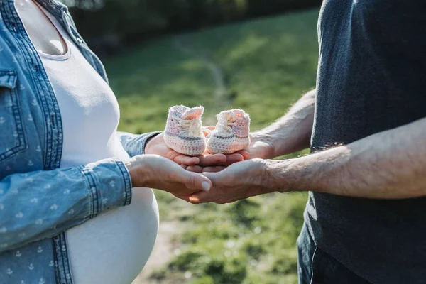 Ein Mann Mit Schwangerer Frau Hält Babyschuhe Einem Feld — Stockfoto