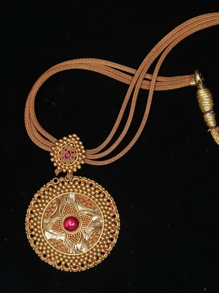 一条女人的古董项链 上面挂着金色的吊坠 镶着红色的珠子和一条金色的项链 背景是黑色的 — 图库照片