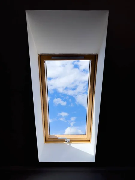 stock image A vertical of the bright, cloudy sky seen from a ceiling window in a dark room