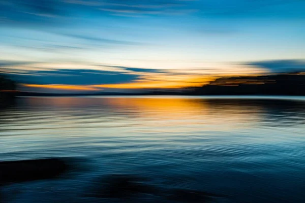 Eine Verschwommene Aufnahme Des Sonnenuntergangs Die Auf Dem Wasser Reflektiert — Stockfoto