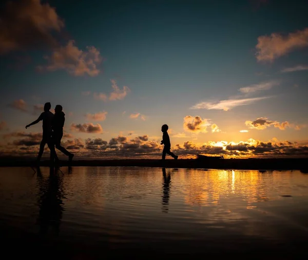 Uma Silhueta Uma Família Caminhando Durante Pôr Sol Com Água — Fotografia de Stock