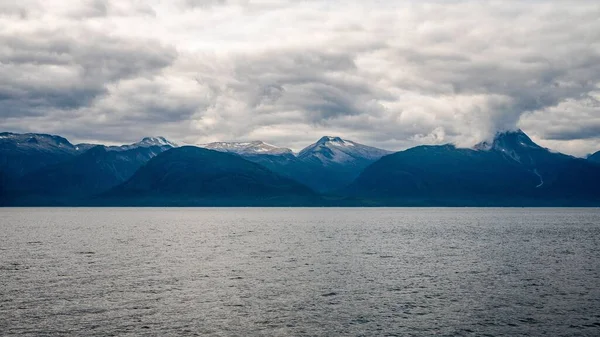 Спокойное Море Большими Снежными Горами Заднем Плане Мрачным Облачным Небом — стоковое фото