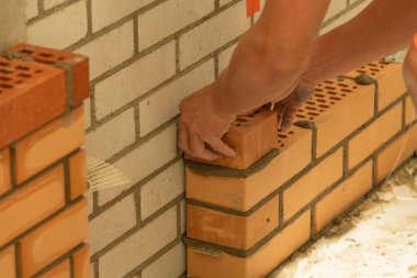 İnşaat alanında tuğla döşeyen birinin yakın çekimi.