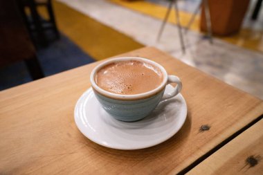 Altında tabak olan küçük bir bardakta sütle lezzetli bir sıcak çikolata.