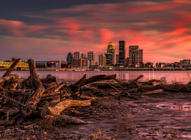 A beautiful shot of chopped tree logs stack against Louisville skyline in Kentucky at pink sunset clipart
