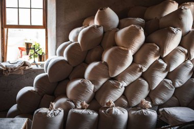 Beyaz çuvallar açık pencerenin yanında beyaz beton bir arka planda üst üste yığılmıştı.