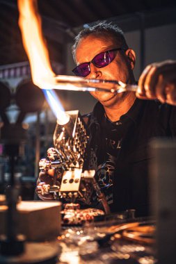 A vertical closeup of a Caucasian glassblower working process at Vienna Cultiva Expo 2021 clipart