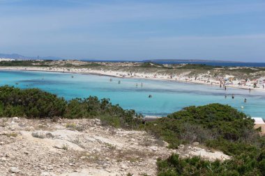 Güneşli bir günde Formentera Adası 'nın kumlu sahillerinde dinlenen insanlar.