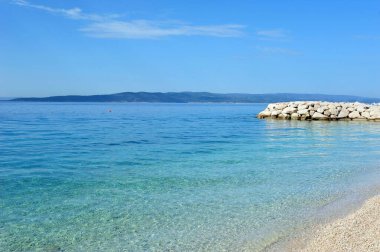 Turkuaz mavi bir okyanus ve mavi bir gökyüzünün altında deniz manzarası.