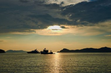 Güçlü güneş ışınlarının altında yüzen yatların siluetlerinin panoramik görüntüsü