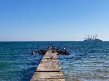 Bir grup genç Balear Adaları 'ndaki mavi bir denizin üzerinde eski bir güvertede vakit geçiriyor.