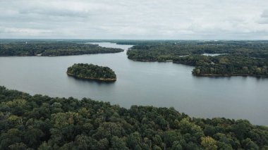 Yoğun ağaçlarla çevrili göl manzarası.