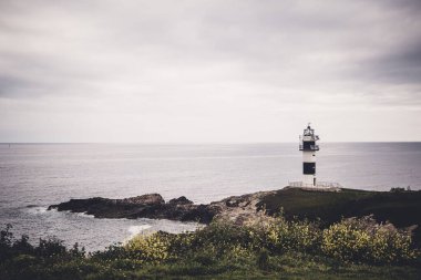 Deniz kıyısında deniz feneri olan gri bulutlu gökyüzü