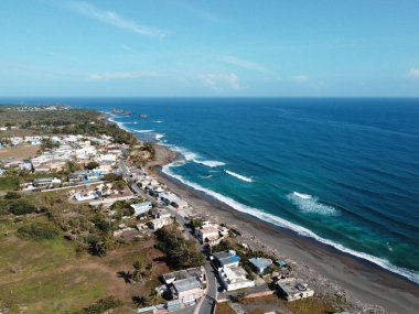 Güneşli bir günde kumlu bir plaja düşen beyaz köpüklü dalgaların hava manzarası.