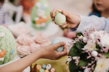 Çocuklar bulanık arka planda renkli Paskalya yumurtalarıyla oynuyorlar.