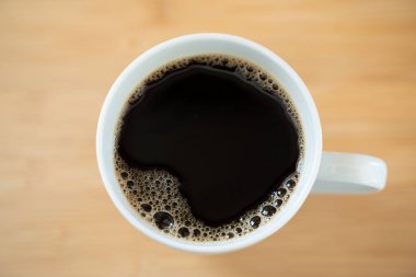 Masada köpüklü bir fincan kahvenin üst görüntüsü.