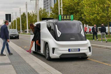 Beyaz bir ETIOCA minibüsten inen bir kadının görüntüsü.