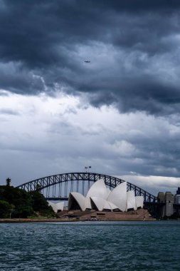 Sydney Opera Binası ve Liman Köprüsü üzerinde fırtınalı bulutların dikey görüntüsü.
