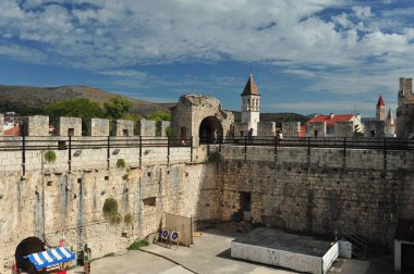 Hırvatistan 'ın Trogir kentindeki Kamerlengo şatosu ve savaş alanı boyunca yürüyen turistler