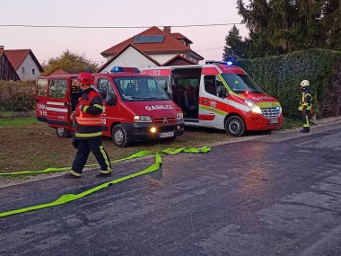 İtfaiyeciler gün batımında evin önüne park etmiş tankerlerin yanında yürüyorlardı.