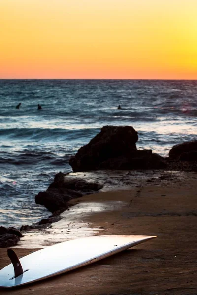 Pionowe Ujęcie Deski Surfingowej Plaży Zachodzie Słońca — Zdjęcie stockowe