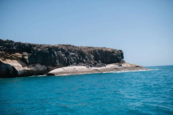 晴れた日には岩場の崖がある穏やかな青い水の海 — ストック写真