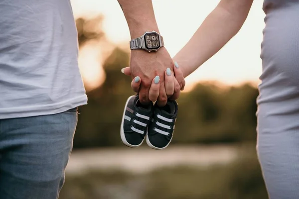 Ett Par Håller Varandras Hand Med Bebisskor — Stockfoto