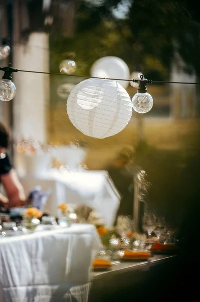 カフェテーブルの近くに吊るされた電球や提灯の垂直ショット — ストック写真