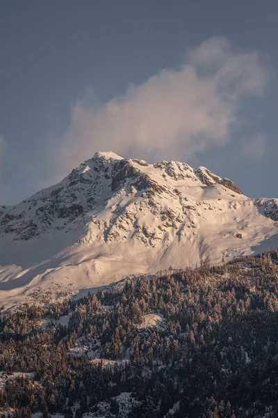 在阳光明媚的日子里 一张覆盖着白雪的阿尔卑斯山的垂直照片 背景是乌云密布的蓝天 — 图库照片