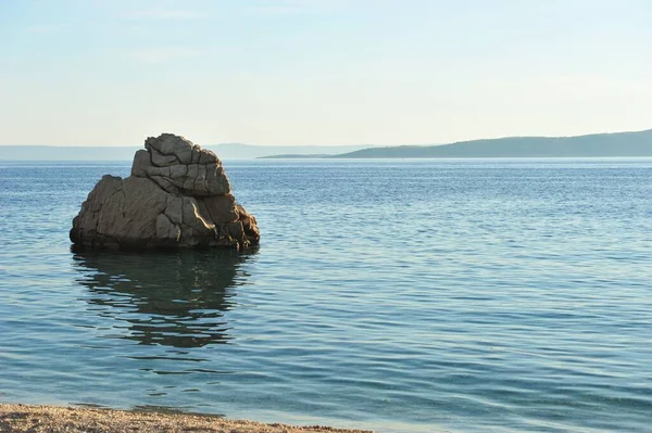 澄んだ空の下で青い海のビーチから大きな岩のクローズアップショット — ストック写真