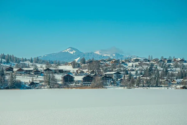 城镇建筑物前的雪地和蓝天下的斜坡 — 图库照片
